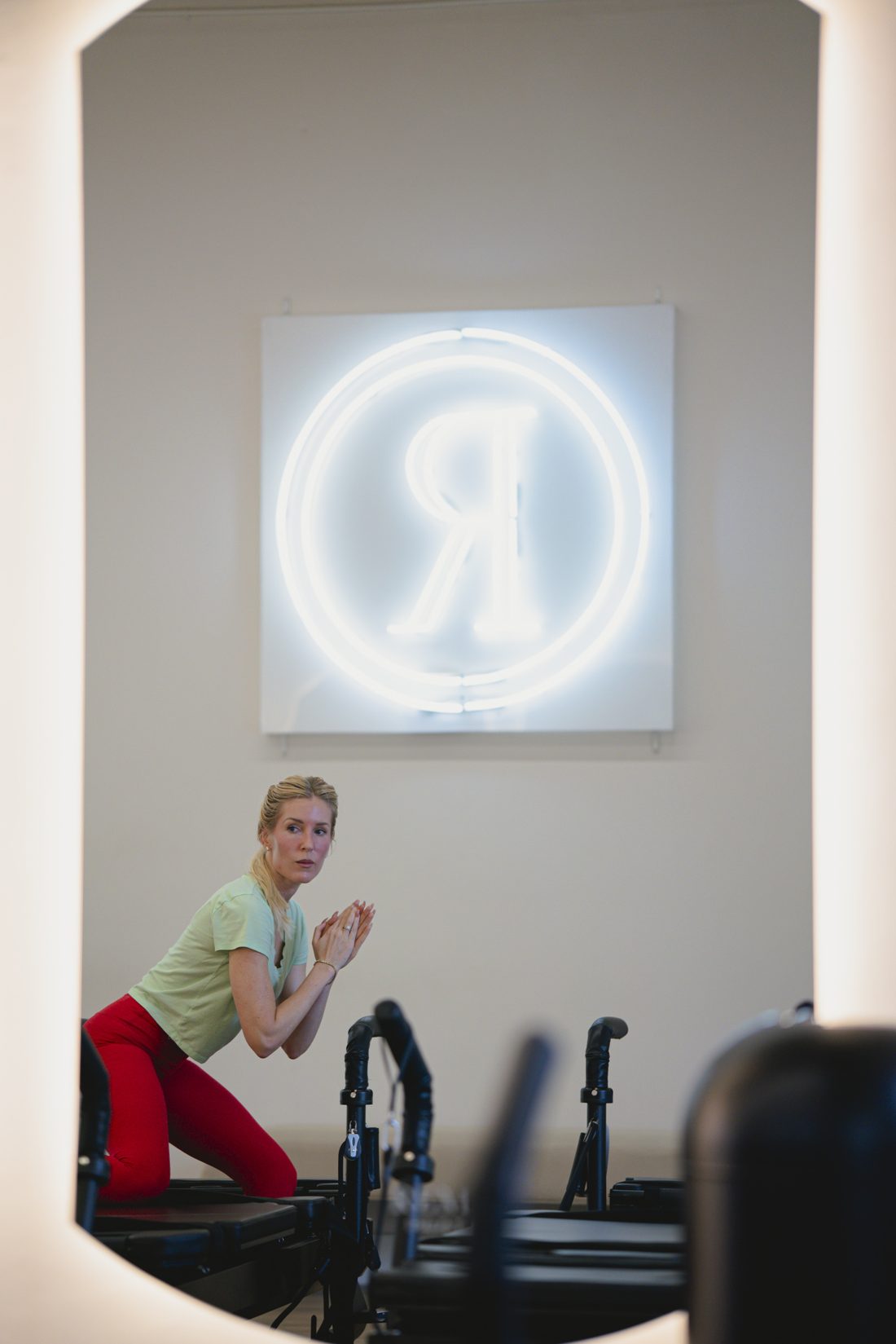 Instructor on an XFormer beneath the Remix neon logo at Remix Modern Pilates in Boca Raton